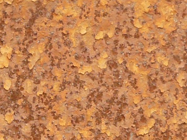 Red rust texture, visible among small flecks of yellow paint and completely covering a a metal surface.